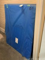 Stack of blue-protected acrylic sheets leaning against a brick wall