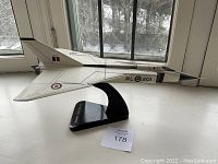 Left-side profile view of white CF-105 Arrow model on black base beside window