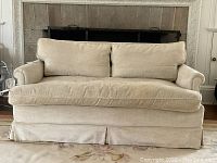 Front view of cream chenille loveseat showing overall shape and skirt