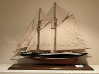 Full side view of the assembled model sailboat on its wooden base