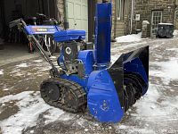 Side view showing blue steel auger housing with rubber track drive