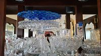 Front view of blue glass cake plate on glass pedestal surrounded by cut glass bowls and dishes.