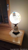 Front lit photo of lamp turned on showing illuminated floral globe.