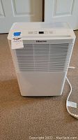 White Hisense dehumidifier full front view on carpeted floor showing power cord and brand name.