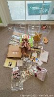 Overview of all items including plastic basket protectors, fabric liners, teddy bear, Wooden basket stand, boxed product, and printed materials spread on floor.