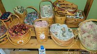 Photo showing 9 woven wooden Longaberger baskets arranged on wooden shelves, each with handles and various fabric liners or none.