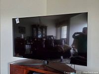 Front view of 65-inch Samsung QLED TV on curved metal stand in living room.