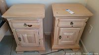 Two matching light wood nightstands side by side showing tops, drawer and cabinet door details.