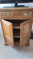 Solid wood armoire with drawer and double doors open showing interior shelving.