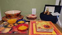 Full view of sunflower ceramic bowls and plates in various sizes and colors alongside sunflower art lamp in box