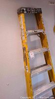 Full view of yellow fiberglass step ladder showing side rails and metal steps.