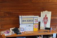Full overview of the items on the wooden bench showing therapy, massage, fitness, and other personal care tools including a muscle anatomy chart and a suction cup set.