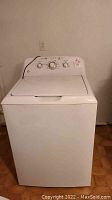 Full frontal view of the white washing machine showing the lid closed and control panel on the top back.