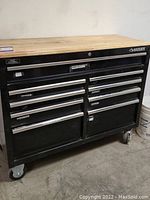 Front view of black Husky rolling tool chest with wooden top and nine drawers on locking wheels