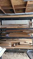 Four shelves filled with various sizes of lumber and plywood, some wood boards laid flat on lower shelves, with two birdhouses on the top shelf.