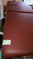 Top view of maroon massage table surface showing fold section and vinyl finish.