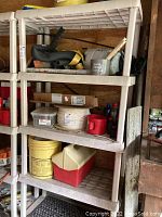 View of entire shelving unit showing three ventilated resin shelves with items on them, shelving is light beige.