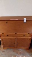 Front view of maple secretary desk showing drop-front, central drawer, and two cabinet doors