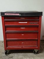 Front view of red Taskforce tool cabinet with four drawers and caster wheels.