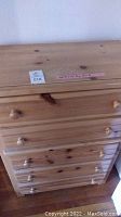 Front view of wooden dresser showing 5 drawers with rounded knobs and wood grain finish.