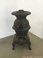 Front view of antique cast iron pot belly stove miniature showing detailed vent front and base