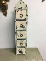 Front view of antique apothecary unit showing five small drawers with chipped cream paint and metal ring pulls.