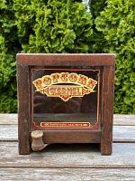 Front view of miniature wooden popcorn vending machine with glass panel showing colorful vintage 'Popcorn Kernel' text.