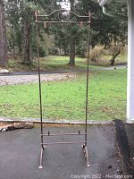 Full view of the tall iron stand placed outdoors showing the overall height and design.