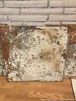 Close-up of one antique tin ceiling tile showing embossed pattern, rust, and paint wear