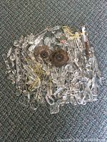 Top view of assorted clear crystal chandelier crystals and two metal flower-shaped pieces on carpeted floor.