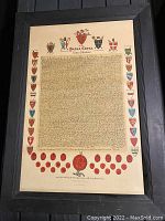 Full view of framed medieval style document with colorful heraldic shields and red wax seals.