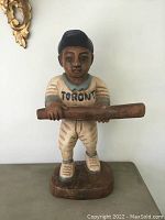 Front view of carved wooden baseball player wearing Toronto Blue Jays uniform holding bat