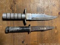 Two vintage military style knives displayed on wooden surface showing overall size and condition