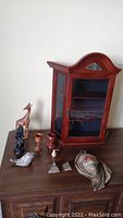 Wooden display case with figurines arranged next to it on a wooden surface showing all items included.
