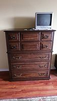 Front view of Kroehler wooden dresser with five drawers, top covered by a small CRT TV.