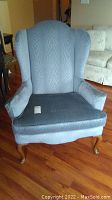 Front view of blue highback wing chair showing fabric upholstery and cushioned seat.
