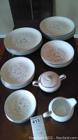 Full view of set items including stack of plates, bowls, sugar bowl, and creamer showing overall condition and wear.