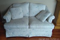Front view of J. Collins Masterpiece loveseat showing two loose cushions, floral upholstery, and skirted base.