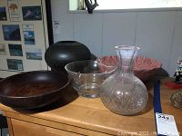 Five bowls and one vase on a wooden surface near a window