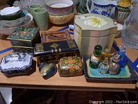 Overall view showing various decorative trinket boxes, ceramic and glass vessels on a wooden table.