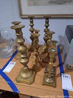 Top and side view of eight brass candle holders arranged on a wooden surface.