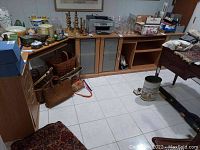 Full view of executive desk in four modules along basement wall, showing drawers, cabinet doors, and surface with various household items.