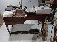 Full view of the wood desk with dark finish and Formica top, showing items placed on top and a case leaning against the legs.