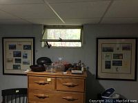 Photo of a basement dresser with two frames mounted on the wall above it, showing the location and relative size of the framed items.