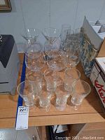 Overall view of collection including multiple clear etched glasses arranged on a table showing variety of shapes and sizes
