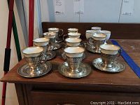 Ten teacup-and-holder sets arranged with saucers on wooden surface