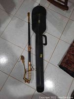 Overhead view showing saber, scabbard and carrying case on tiled floor