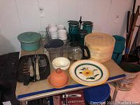Photo shows assortment of kitchen items on table including ramekins, bamboo steamer, storage jars, coffee carafes, baking dish, and utensils.