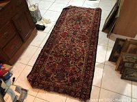 Full view of the entire runner rug displaying its length and varied colors in an indoor tiled setting.