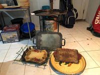 Photo of serving platters on a tiled floor showing various sizes and materials including metal, wood, and glass with folding stand